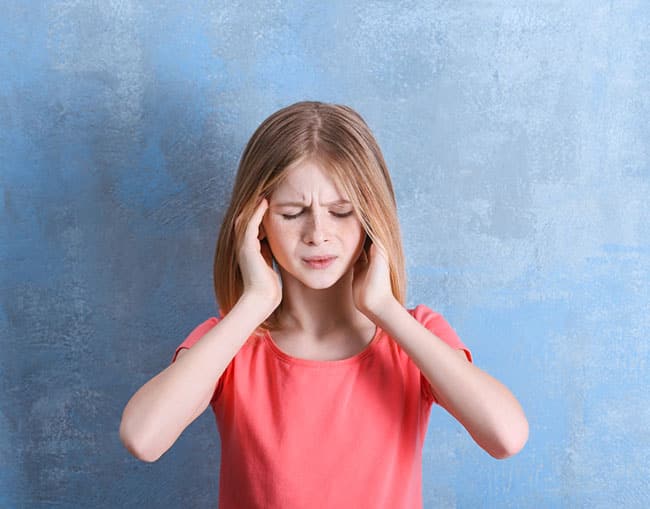 the child holds his head with his hands because she needs to treat a child migraine with Botox