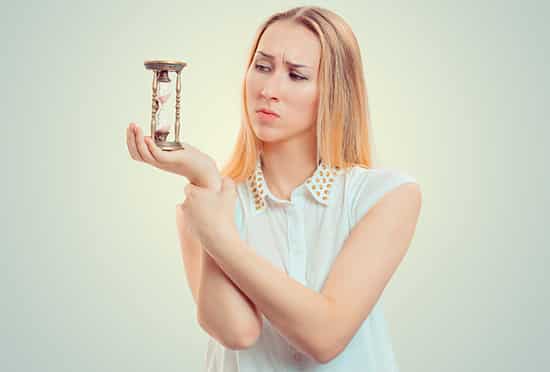 The girl looks at the hourglass in her hand