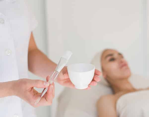 the doctor prepares a woman for skin peeling