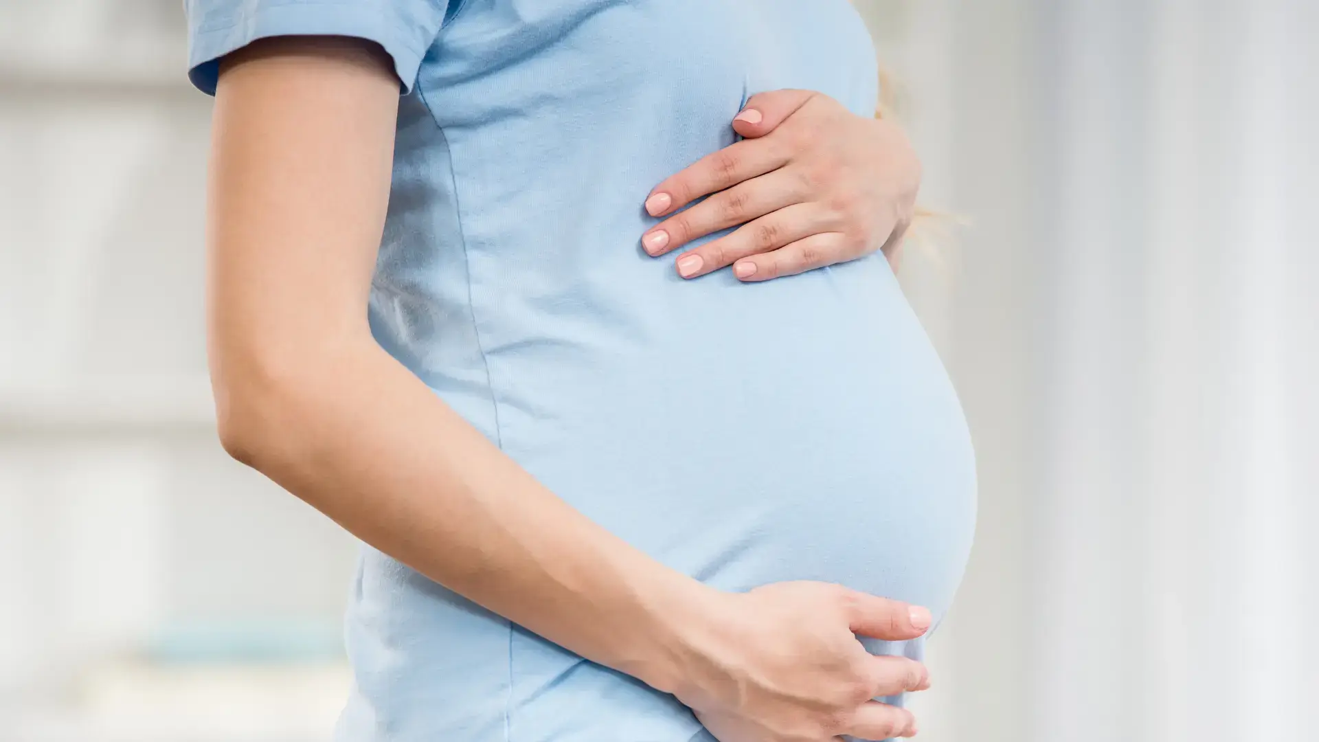 A pregnant individual holding their belly.